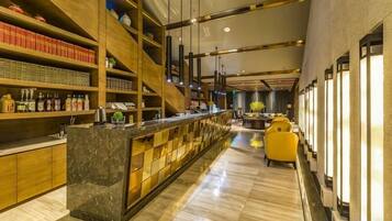 A bar area with a long counter, shelves with bottles, and a seating area with yellow chairs.