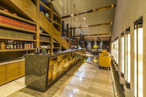 A bar area with a long counter, shelves with bottles, and a seating area with yellow chairs.
