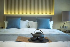 A neatly made bed with a tea set on a placemat, pillows, and a headboard with vertical slats. - OffCN HY Hotel (Nanjing)