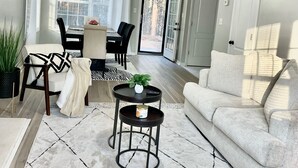 A living room with a sofa, coffee table, and dining area with chairs and a table.