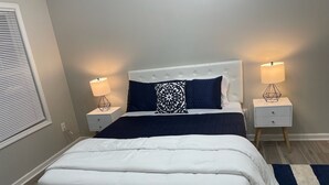 A neatly arranged bedroom with a white bed, two nightstands, and a blue and white striped rug.
