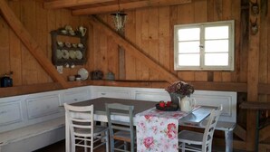 A wooden dining area with a table and chairs, a window, and a shelf with dishes. - Family-friendly temporary home (Horben)