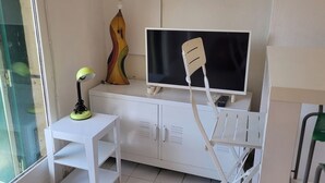 A small room with a white desk, a television, and a decorative guitar.