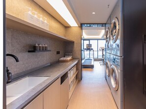 A modern kitchen with a large sink, built-in shelves, and a laundry area with stacked washing machines. - JI Hotel Nanning Dongge Road (Nanning)