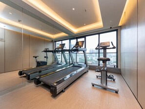 Une salle de sport moderne équipée de tapis de course, d’un vélo d’appartement et d’un rameur.
