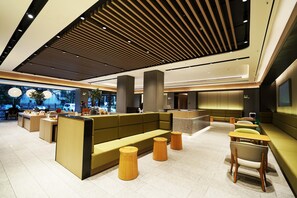 A modern hotel lobby with a central seating area, wooden tables, and a high ceiling with linear lighting. - JI Hotel Nanning Dongge Road (Nanning)