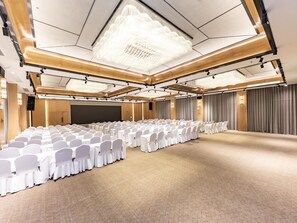 A conference room with rows of white chairs, a large screen, and a chandelier. - JI Hotel Nanning Dongge Road (Nanning)