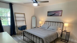A bedroom with a bed, desk, chair, and a ceiling fan.