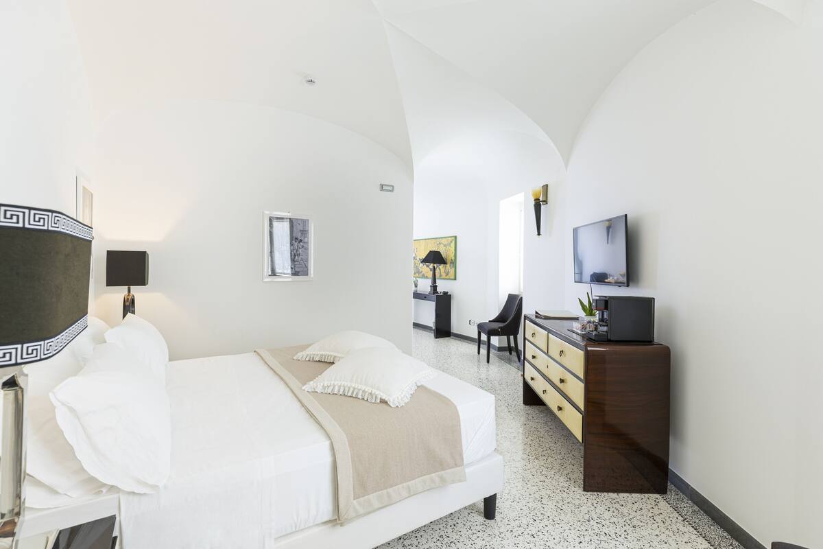 A modern hotel room with a large bed, a desk, a chair, and a TV.