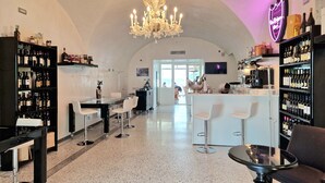 Un espace bar agrémenté d’un lustre, de bouteilles de vin et de sièges.