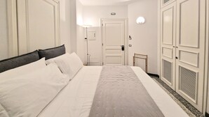 Une chambre d’hôtel avec un grand lit, une table de chevet, une lampe et une armoire.