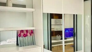 A bedroom with a white wardrobe, a bed, and a desk with a computer. - Convenient 1BR Beside SM Mall (Davao City)