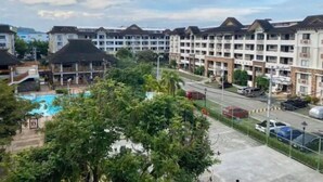 A multi-story hotel with a swimming pool and lush greenery. - Convenient 1BR Beside SM Mall (Davao City)