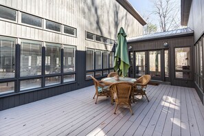 Une terrasse avec une table et des chaises, un parasol vert et une vue sur un immeuble aux grandes fenêtres.