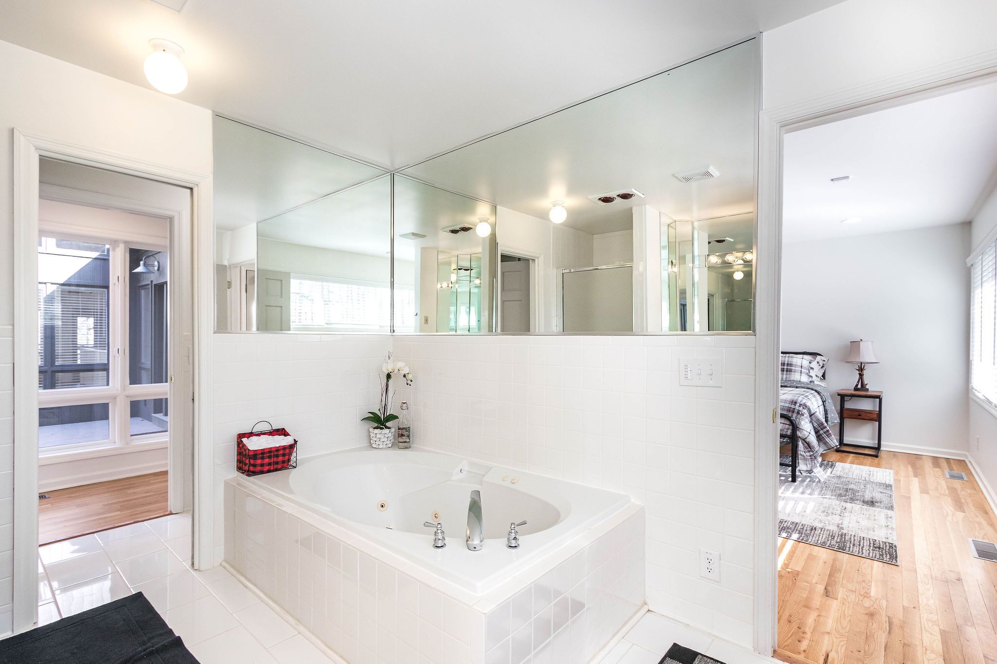 Ein modernes Badezimmer mit einem großen Spiegel, einer freistehenden Badewanne und einem kleinen Nachttisch mit Lampe.