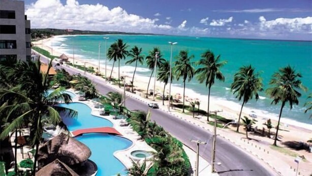 Un resort con piscina, playa y palmeras.