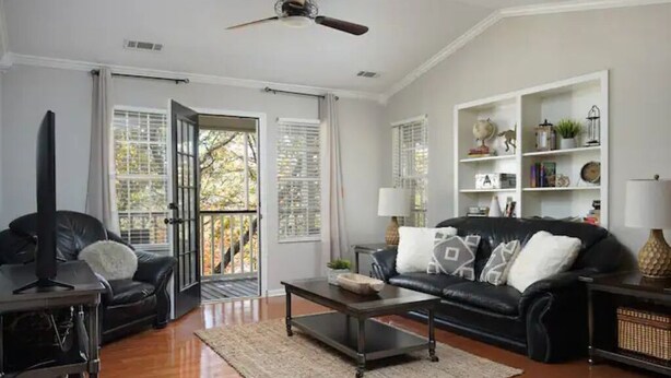 A living room with a black leather sofa, a coffee table, and a bookshelf.