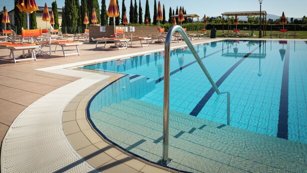 A swimming pool with sun loungers and umbrellas, surrounded by trees and a clear sky. - Residence Borgo Verde (Rosignano Marittimo)
