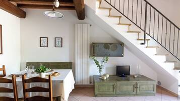 Un coin repas avec une table dressée pour deux personnes, un meuble vert et un escalier.