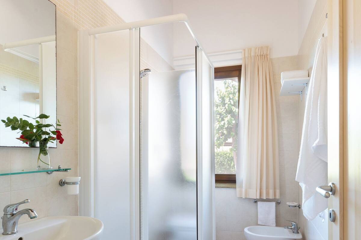 A bathroom with a glass-enclosed shower, a sink, a toilet, and a mirror.