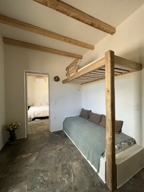Ein Schlafzimmer mit Etagenbett, Steinböden und einem Holzbalken an der Decke.