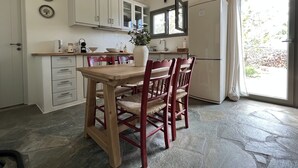 A kitchen with a wooden table and chairs, white cabinets, and a large window. - Countryside farm family house, private, calm with mountain views (Sangri)