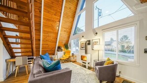 Geräumiges Loft mit hohen Decken, Holzbalken, Kamin und großen Fenstern.