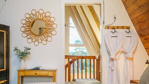 Ein Schlafzimmer mit einem Bett, einem Nachttisch mit einem Buch, einem Spiegel und einer Zimmerpflanze.