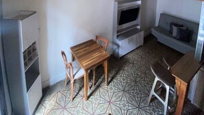 A compact room with a wooden ceiling, a TV, a sofa, a small table, and a chair. - 1CA-1D APARTAMENTO DUPLEX EN GETSEMANI (Cartagena)