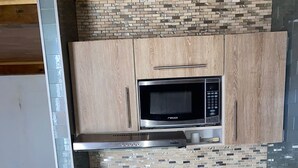 A compact kitchen with wooden cabinets, a built-in microwave, a gas stove, and a sink. - 1CA-1D APARTAMENTO DUPLEX EN GETSEMANI (Cartagena)