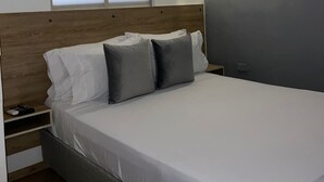 A modern bedroom with a large bed, a nightstand, a window, and a wall-mounted light. - 1CA-1D APARTAMENTO DUPLEX EN GETSEMANI (Cartagena)