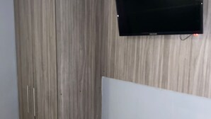 A room with a wooden wardrobe, a flat-screen TV mounted on the wall, and a light-colored floor. - 1CA-1D APARTAMENTO DUPLEX EN GETSEMANI (Cartagena)