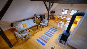 A cozy loft-style living room with a wooden floor, a sofa set, a fireplace, and a dining area with a table and chairs. - Chalupa na Fryšavě (Frysava pod Zakovou horou)