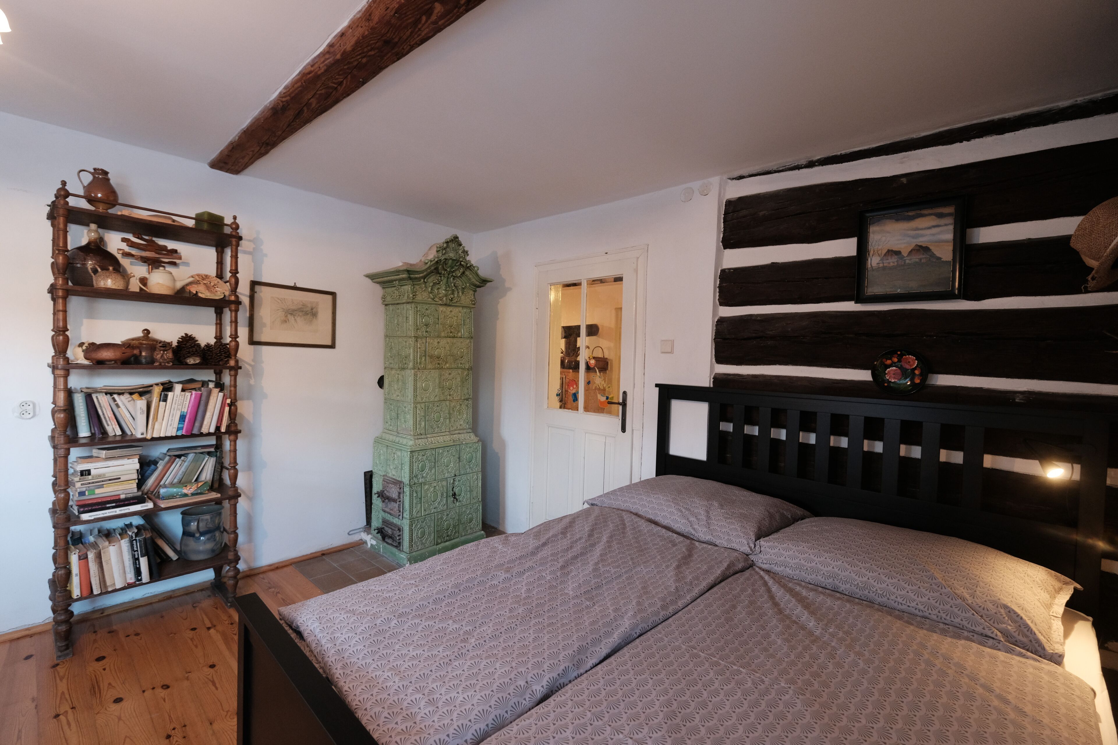 Ein Schlafzimmer mit einem Bett, einer Holzbibliothek, einem grünen Schrank und einem schwarzen Kopfteil mit einem Bild.
