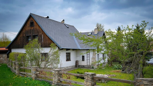 A rustic house with a stone wall and wooden fence, surrounded by greenery and a clear sky. - Chalupa na Fryšavě (Frysava pod Zakovou horou)