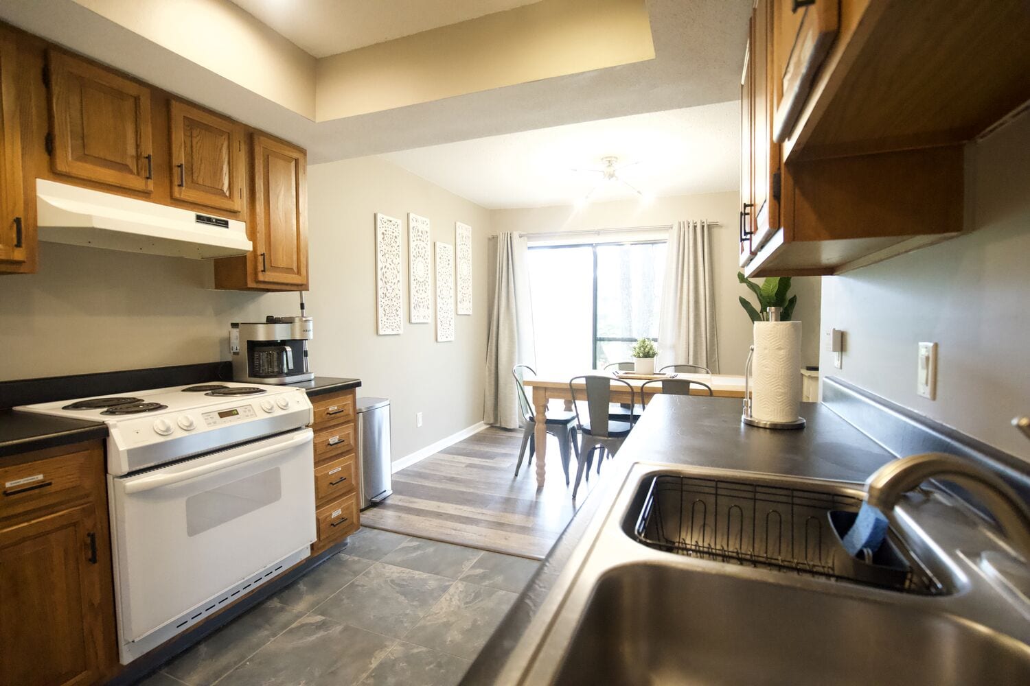 A modern kitchen with wooden cabinets, a stove, and a sink.