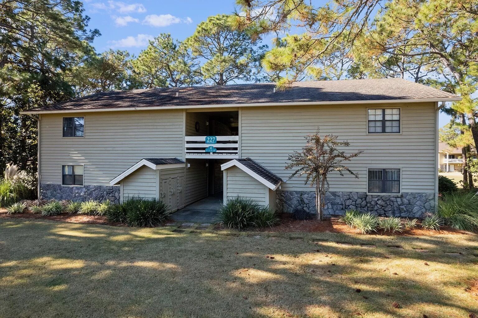 A two-story house with a garage, a small porch, and a stone accent wall.