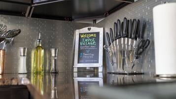 A kitchen counter with a sign reading "Welcome to Depot Village" and a variety of kitchen utensils and bottles.