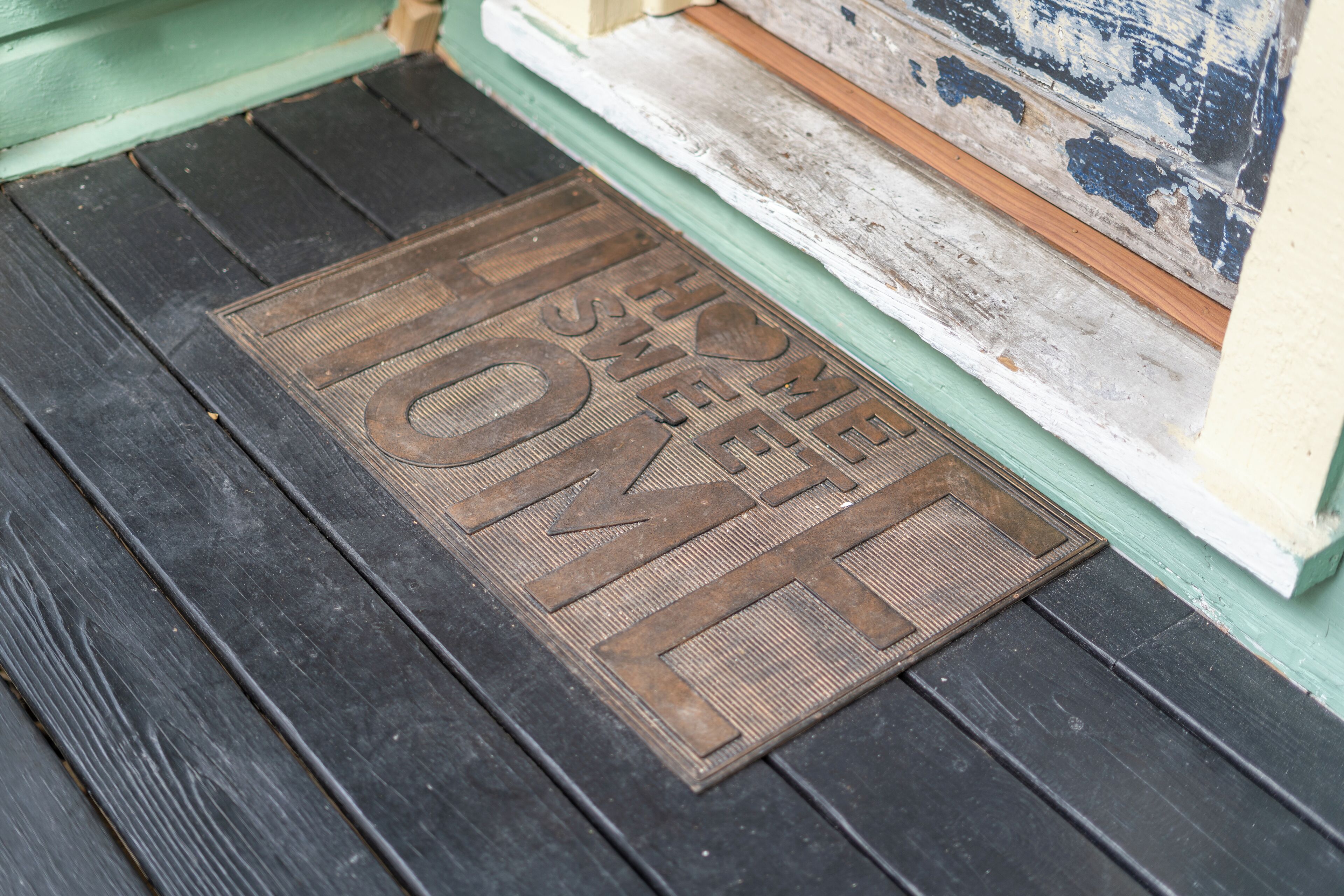 A wooden door with a metal doormat that reads "HOME SWEET HOME."