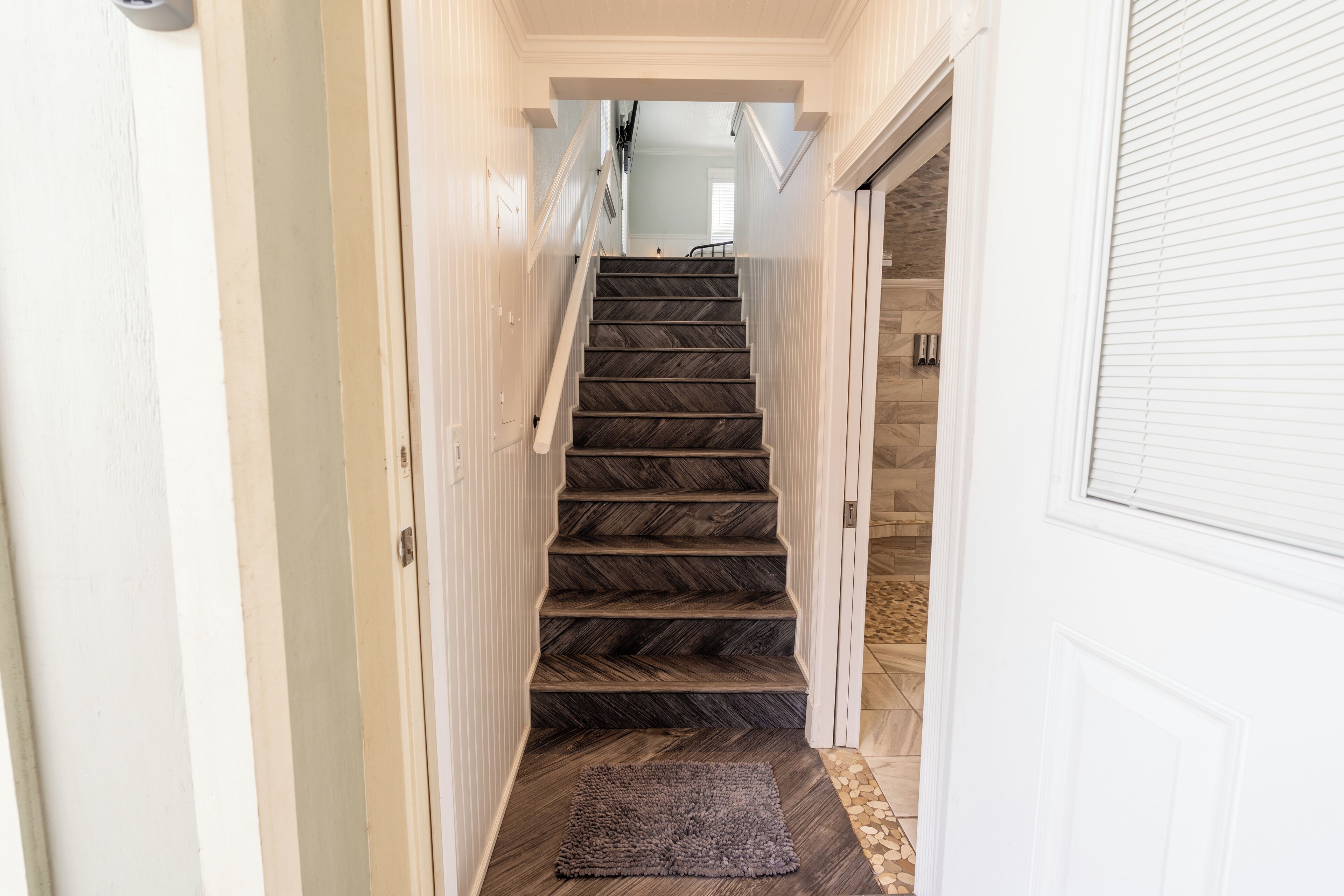 Un escalier avec des marches en bois foncé et un tapis au bas.