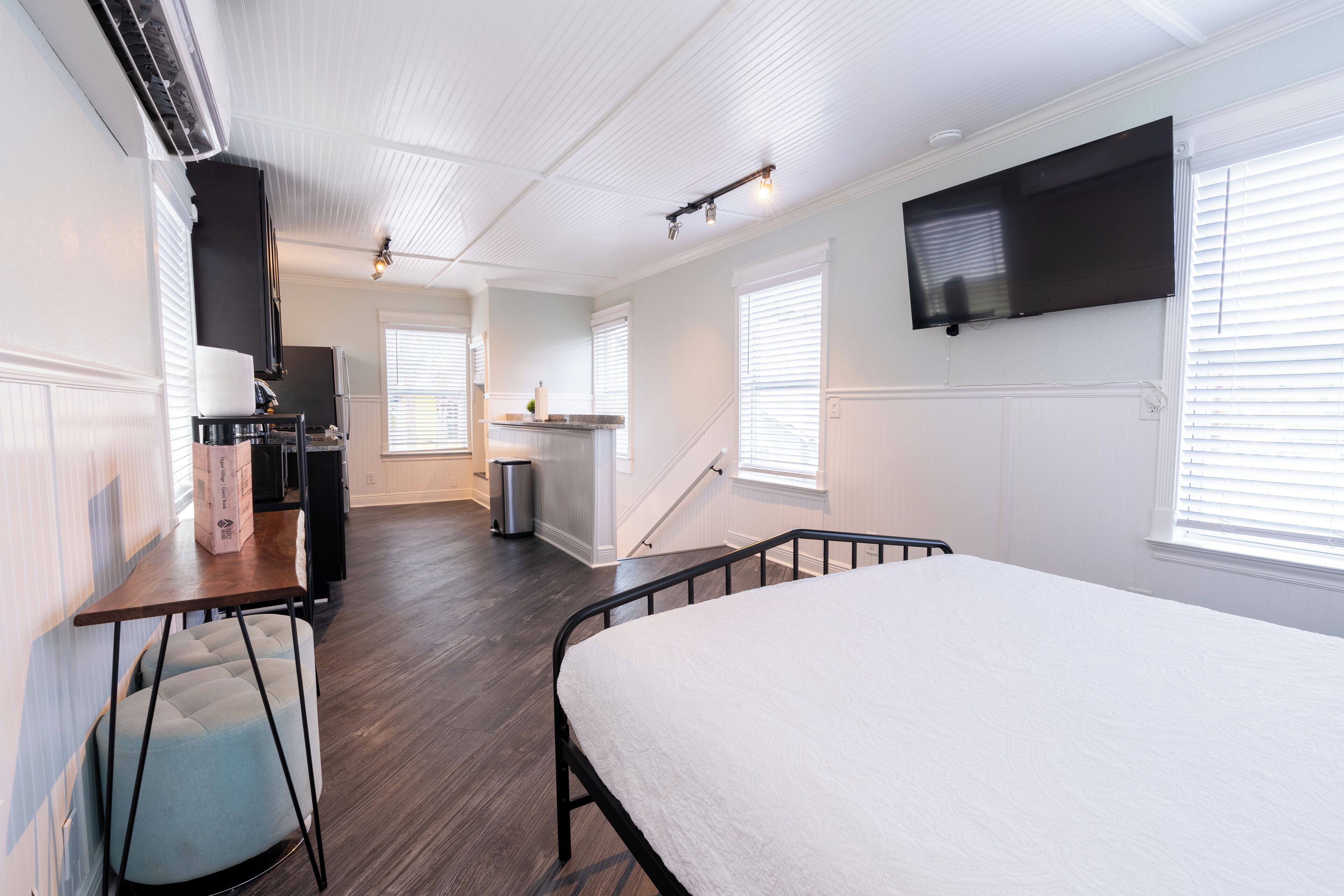 Una habitación moderna y luminosa con una cama grande, un escritorio y una kitchenette.