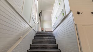 A staircase with dark wooden steps leading to a landing with a small table and chair. - Depot Village (Gainesville)