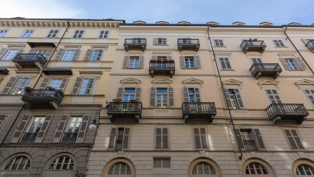 Ein mehrstöckiges Gebäude mit Balkonen, Rundbogenfenstern und einem Laden mit einer Schaufensterschild.