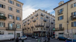 Ein mehrstöckiges Gebäude mit Balkonen, Blick auf die Straße und parkenden Autos.