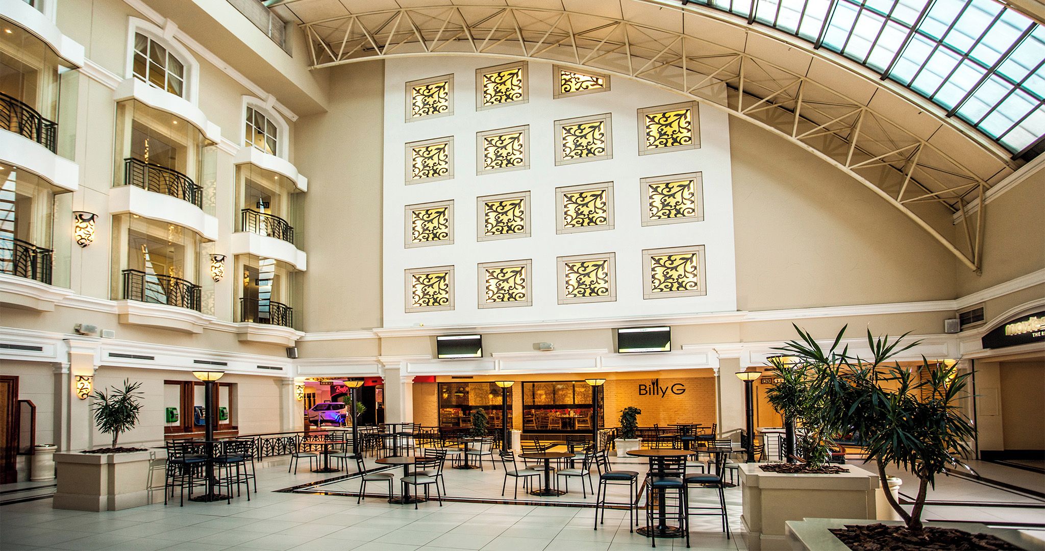 Un vaste atrium à plusieurs niveaux, doté d’un espace central ouvert avec des tables et des chaises, entouré de balcons et de boutiques.