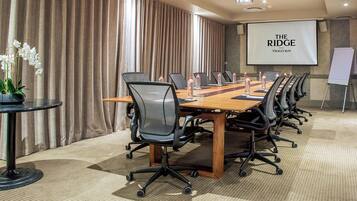 A conference room with a long table, chairs, a projector screen, and a whiteboard.