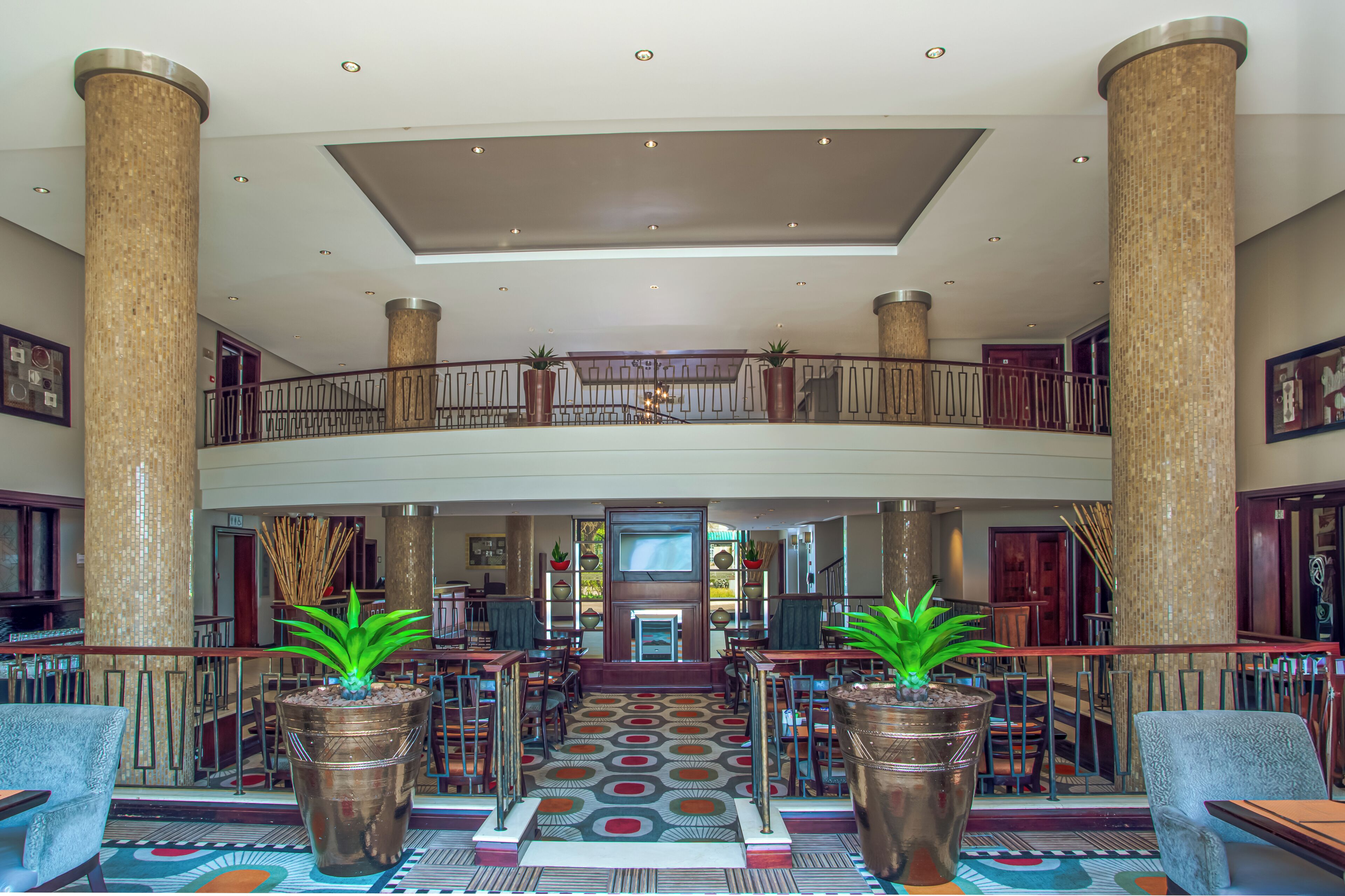 A spacious lobby with high ceilings, large columns, and a central staircase.