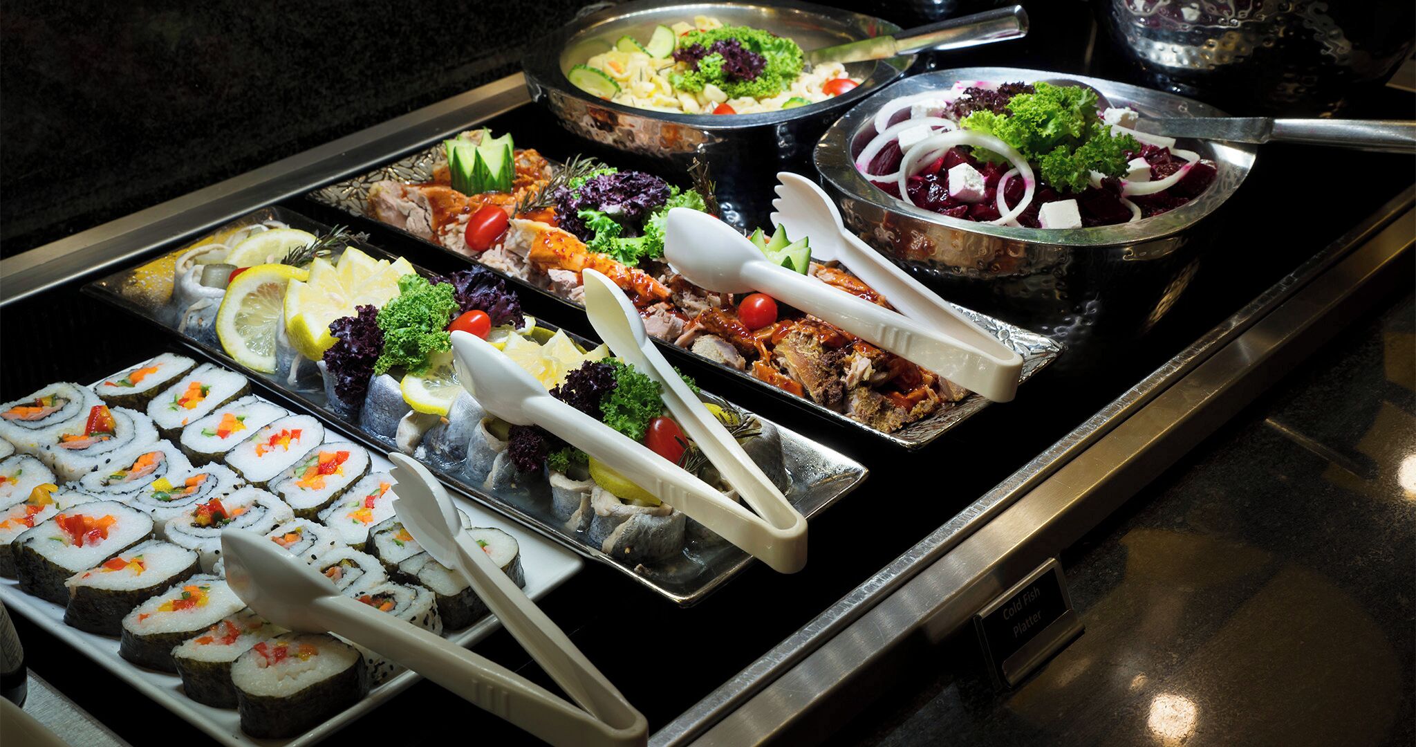 Ein Buffet mit verschiedenen kalten Speisen, darunter Sushi, Salate und Fischplatten.