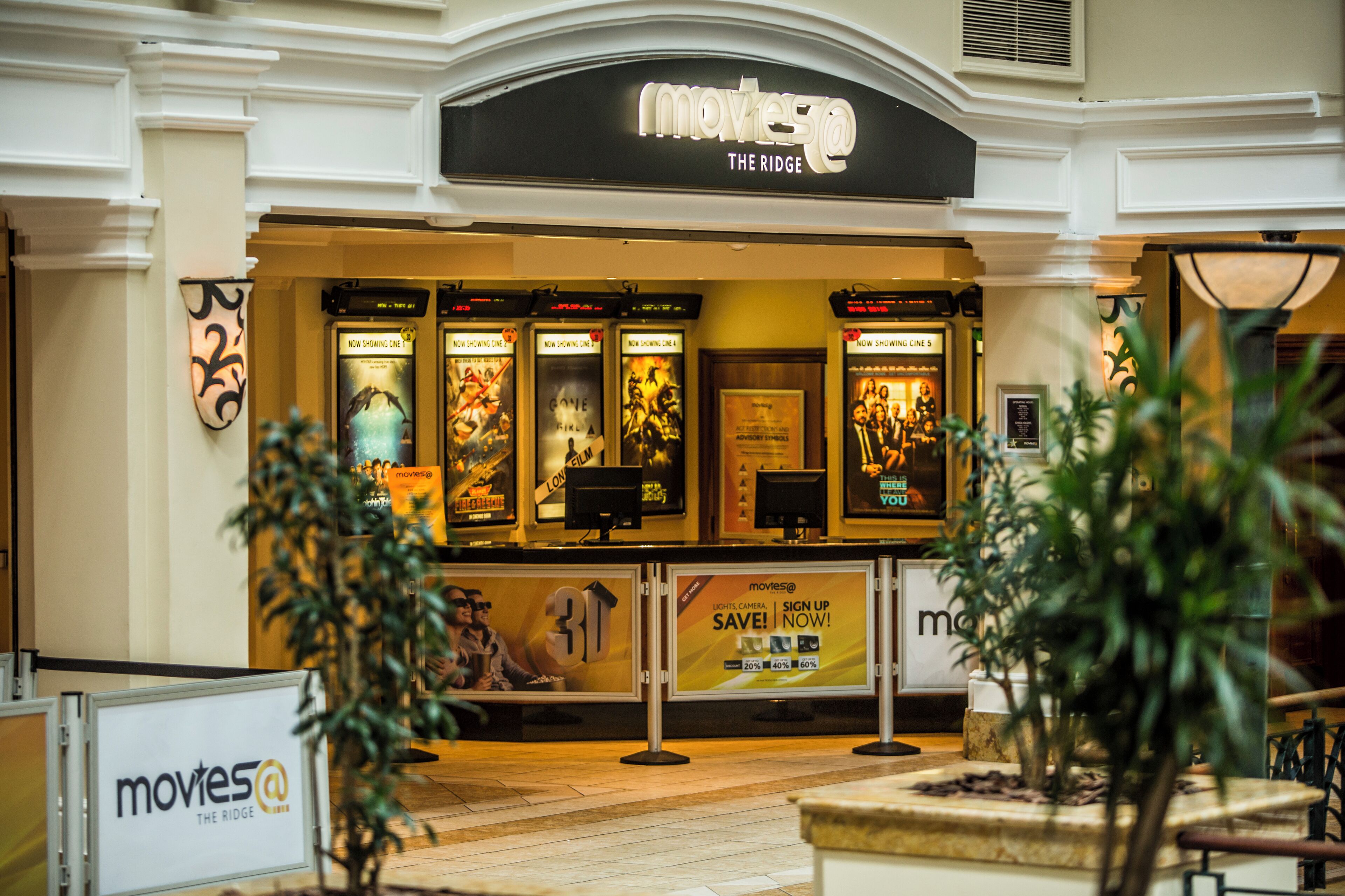 Un cinéma Movies@The Ridge avec une devanture où sont affichées des affiches de films et un panneau indiquant une réduction de 30 % pour les nouveaux abonnés.