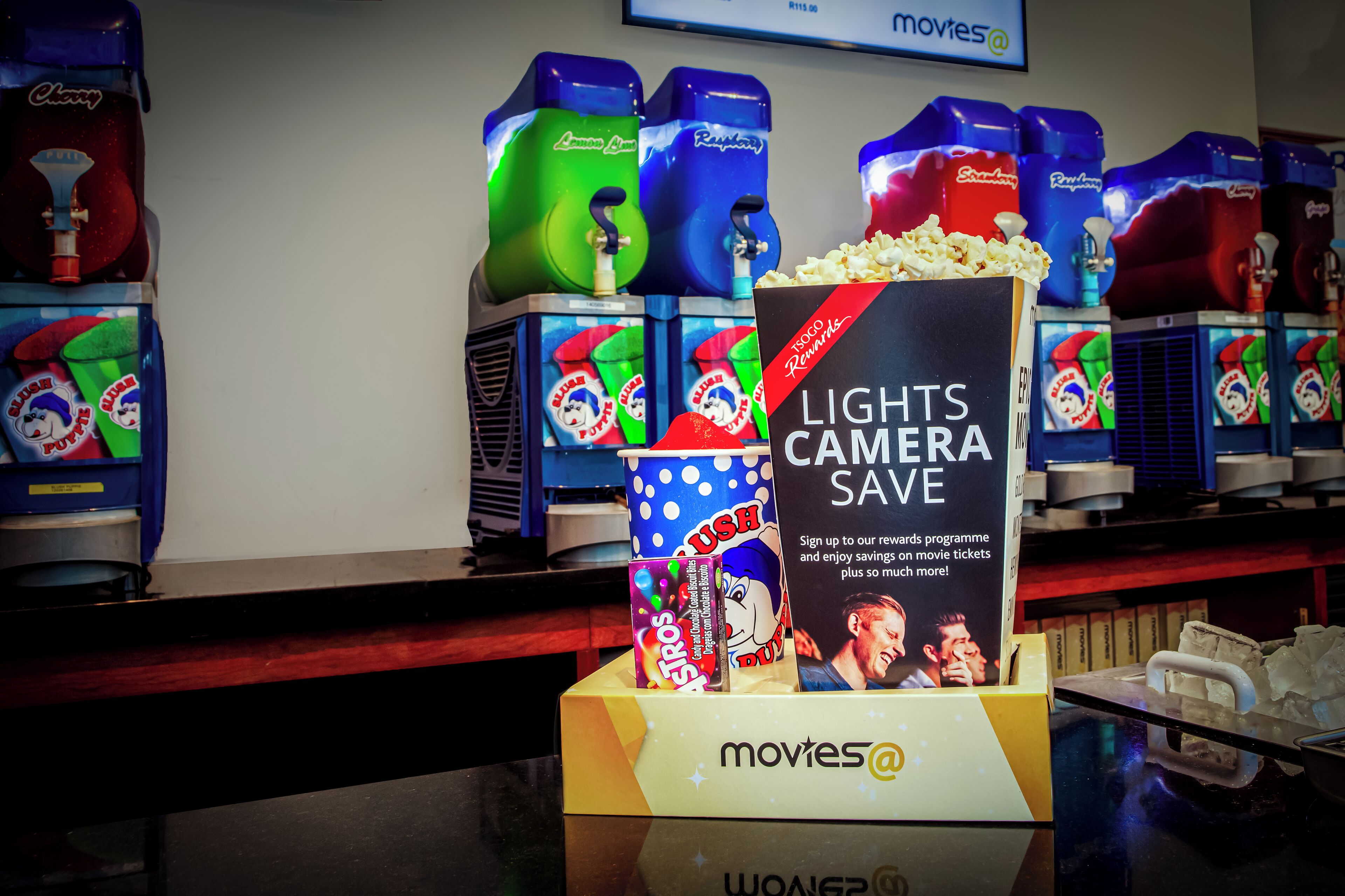 A cinema with popcorn machines and a promotional display for a movie ticket savings program.